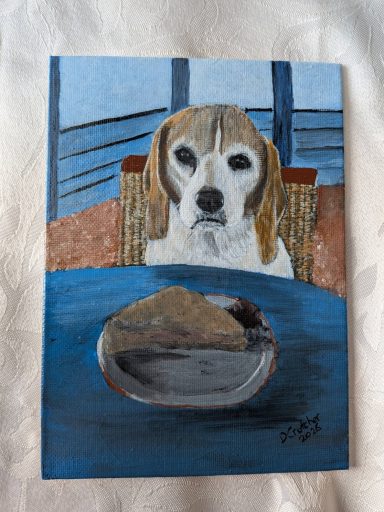 Beagle sat at a table on a chair looking at a piece of pie on a plate